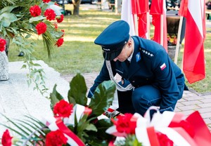 policjant składający wieniec pod pomnikiem upamiętniającym ofiary bombardowania węzła kolejowego Brzesko-Słotwina.