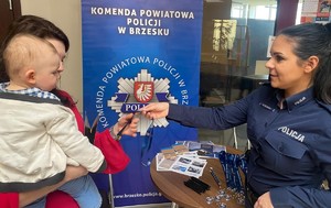 policjantka wręczająca brelok do kluczy dla kobiety trzymającej na ręku dziecko