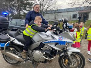 przedszkolak siedzący na policyjnym motocyklu, obok stoi policjantka