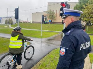 policjant oceniający przejazd uczennicy na rowerze po miasteczku rowerowym