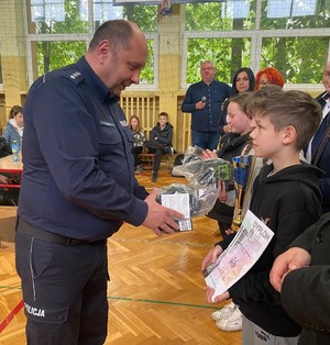 I zastępca komendanta powiatowego policji w Brzesku wręcza nagrodę uczestnikowi jednej ze zwycięskich drużyn