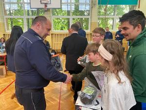 I zastępca komendanta powiatowego policji w Brzesku wręczający nagrodę uczniowi jednej ze zwycięskich drużyn