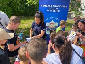 policjantka rozdająca odblaski przy stoisku profilaktycznym