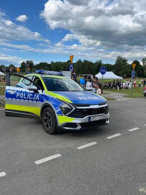 uczestnicy pikniku stojący przy radiowozie