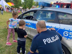 policjant kucający przy dziecku oglądającym kajdanki