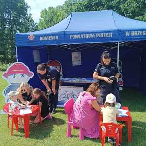 policjantki przyglądające się dzieciom malującym rysunki przy stoisku profilaktycznym