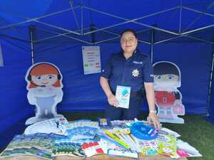 policjantka trzymająca ulotkę dotyczącą bezpieczeństwa nad wodą, pozująca do zdjęcia w namiocie profilaktycznym