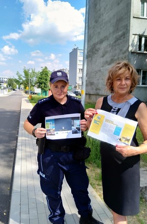 policjantka pozująca do zdjęcia z przewodniczącą osiedla Kopaliny-Jagiełły, w rękach trzymają ulotkę dotyczącą zabezpieczenia domu przed włamaniem