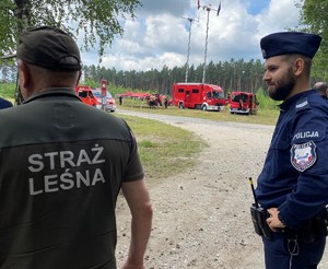 policjant rozmawiający z funkcjonariuszami straży leśnej