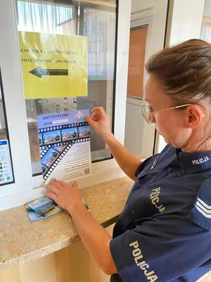 policjantka zawieszająca plakat o konkursie w placówce, gdzie odbywa się kolonia