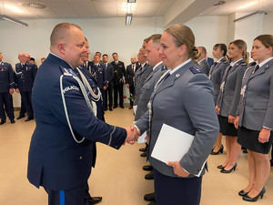 zastępca komendanta wojewódzkiego policji wręczający akt mianiowania i gratulujący awansu policjantce