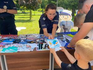 policjantka wręczająca chłopcu ulotkę dotyczącą bezpieczeństwa nad wodą