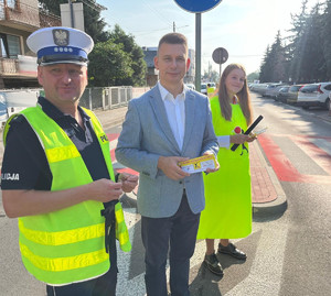 dyrektor małopolskiego ośrodka ruchu drogowego w tarnowie w towarzystwie uczennicy i naczelnika wydziału ruchu drogowego brzeskiej komendy stoją przy przejściu dla pieszych