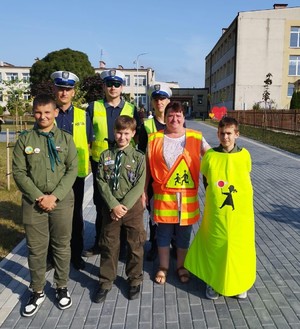 zdjęcie grupowe policjantów wydziału ruchu drogowego z harcerzami i opiekunki przeprowadzającej uczniów przez przejście