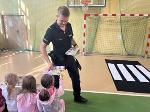 policjant rozdający plany lekcji uczniom podczas spotkania