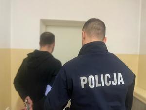 policjant doprowadzający poszukiwanego do pomieszczeń dla osób zatrzymanych