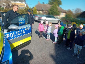 policjanci z grupą przedszkolaków stojący przy radiowozie