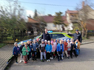 zdjęcie grupowe dzieci z policjantami na tle radiowozu