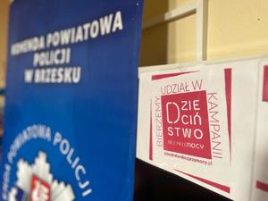 plakat dzieciństwo bez przemocy, w tle baner komendy powiatowej policji w Brzesku