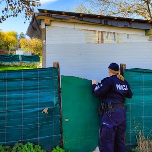 policjantka zaglądająca przez plandeki do miejsca przebywania osób zagrożonych wychłodzeniem