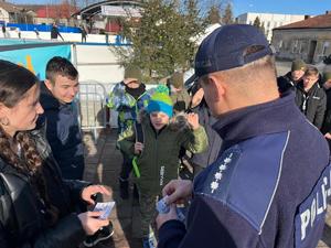 kierownik dzielnicowych rozdający ulotki dot. bezpieczeństwa podczas ferii