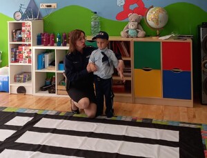 policjantka kucająca przy przedszkolaku przebranego za policjanta