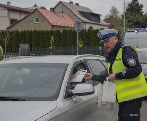 Policjant podczas przekazywaniu kierowcy materiałów profilaktycznych