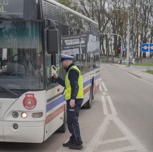 Policjant Wydziału Ruchu Drogowego podczas przekazywania kierowcy autobusu alkotestu