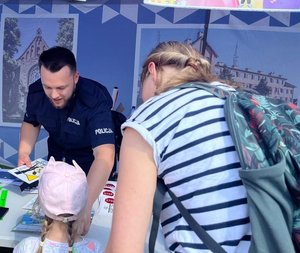 policjant wręczający dziecku materiały profilaktyczne