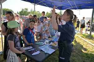 policjantka przy stoisku profilaktycznym z uczestnikami