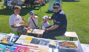 policjantka z uniesionym kciukiem pozująca do zdjęcia z trzema chłopcami