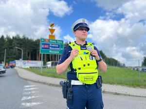 policjant ruchu drogowego na skrzyżowaniu, w tle protestujący