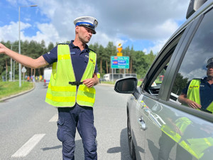 policjant ruchu drogowego stojący przy samochodzie