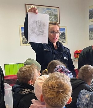 policjantka pokazująca zabezpieczony ślad dłoni na kartce papieru