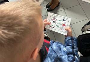 dziecko trzymające kartkę z numerem alarmowym