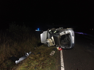 samochód leżący na bok, w tle policyjny radiowóz