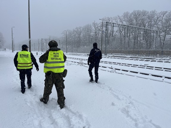 funkcjonariusz policji, wojsk obrony terytorialnej i straży ochrony kolei patrolują okolice infrastruktury kolejowej