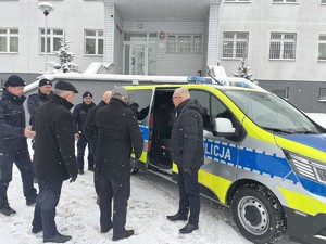 przedstawiciele władz samorządowych z policjantami oglądają wnętrze radiowozu