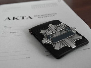 policyjna odznaka leżąca na obwolucie akt sprawy