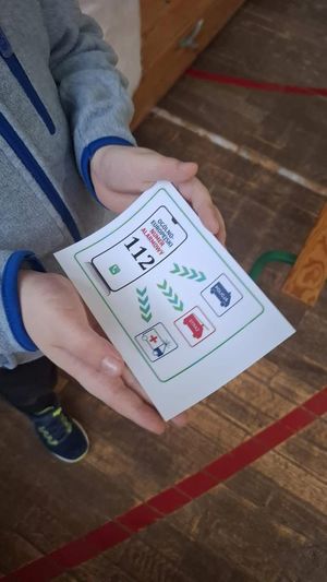 kartka z numerem alarmowym trzymana przez chłopca