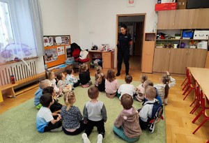 policjantka stojąca przed grupą siedzących na dywanie przedszkolaków (2)