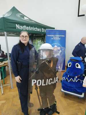 policjantka pozująca do zdjęcia z dzieckiem w kasku policyjnym i tarczą