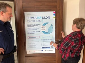 dzielnicowy z seniorką przy plakacie