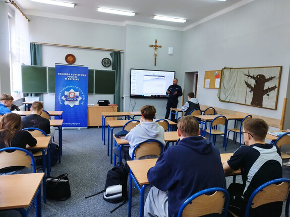 zastępca komendanta przemawia do uczniów siedzących przy ławkach