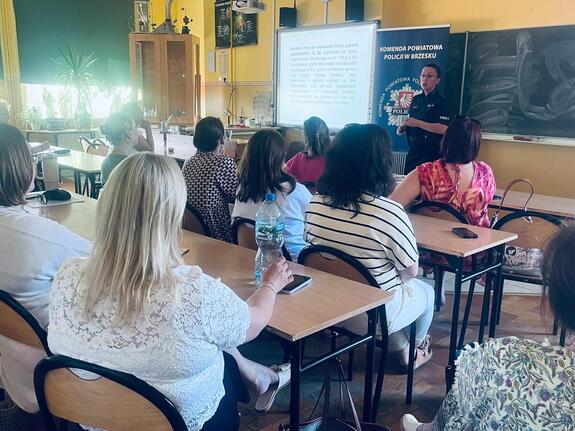 policjantka przemawiająca do kadry pedagogicznej w sali lekcyjnej
