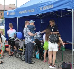 policjantka rozdająca ulotki uczestnikom pikniku