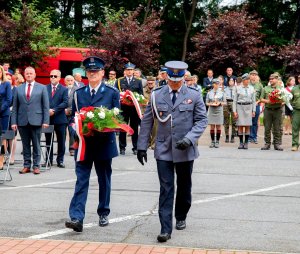 policjanci niosą uroczystą wiązankę kwiatów