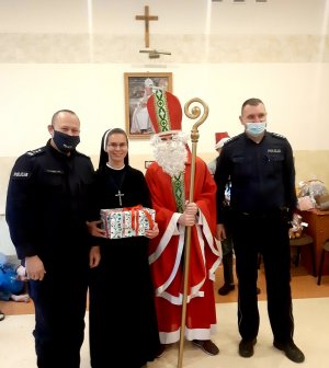 Komendant, policjant wraz z siostrą zakonną oraz Św. Mikołajem pozujący do wspólnego zdjęcia