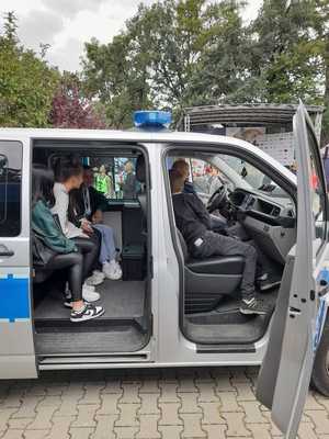 dzieci i młodzież siedzące w policyjnym radiowozie razem z policjantem
