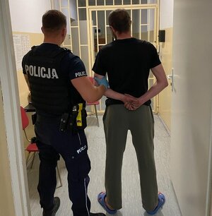 policjant prowadzący nietrzeźwego kierującego do pomieszczeń dla osób zatrzymanych